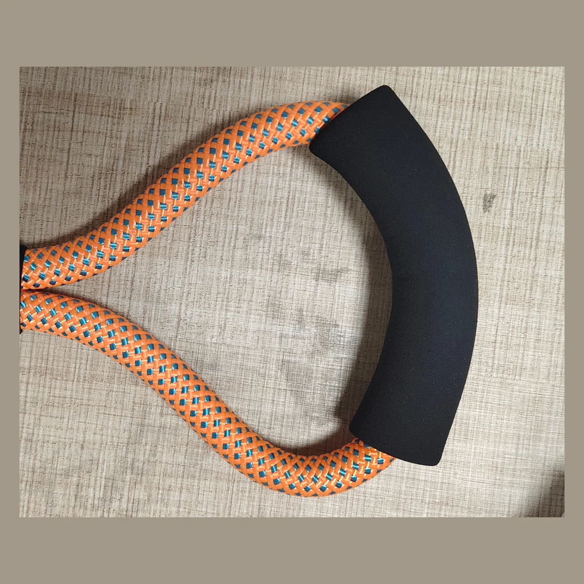 Black foam padded handle and loop connection on an orange braided dog leash