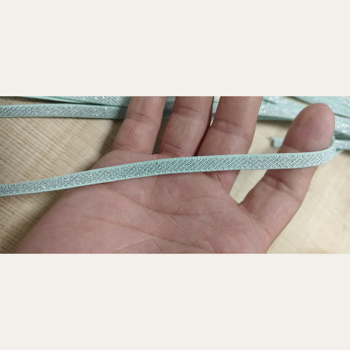 Hand scale view of narrow silver lurex elastic band for shoes and accessories