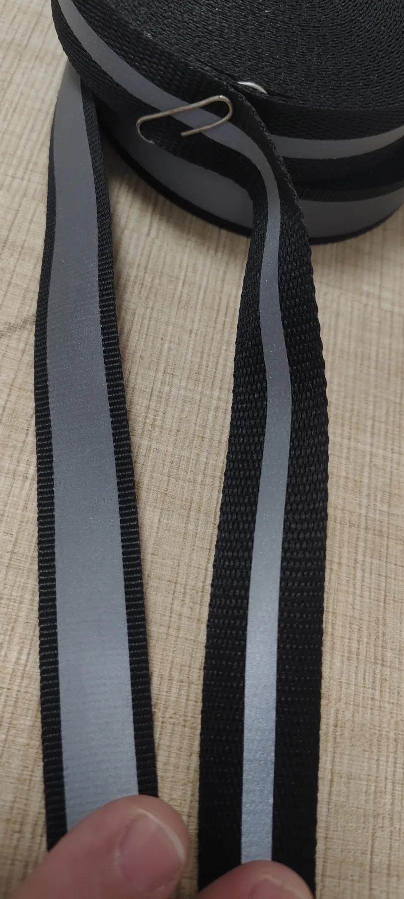 Close-up of black 15mm polyester webbing with applied gray reflective strips