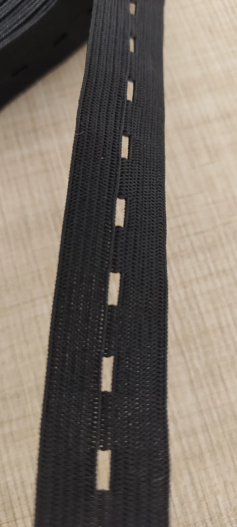 Close-up of regularly spaced openings in black 20mm buttonhole elastic band